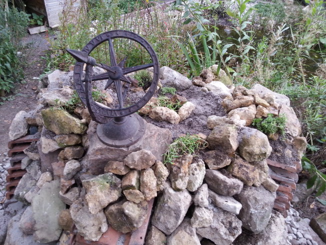 In den Zwischenräumen habe ich dann Bruchsteine aufgeschichtet, habe sie auch auf die Ziegel aufgebracht. Die Mitte habe ich mit einem Erd-Sand-Gemisch aufgefüllt und Steingartenplfanzen finden dort einen tollen Lebensraum. - Sedum, aber auch Thymian, Stängelloser Enzian und andere Gewächse... Die Sonnenuhr muss ich noch richtig ausrichten.