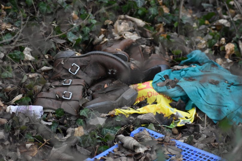 ein paar Schuhe, neben Tüten, Plastikkisten, Textilien und anderem Müll