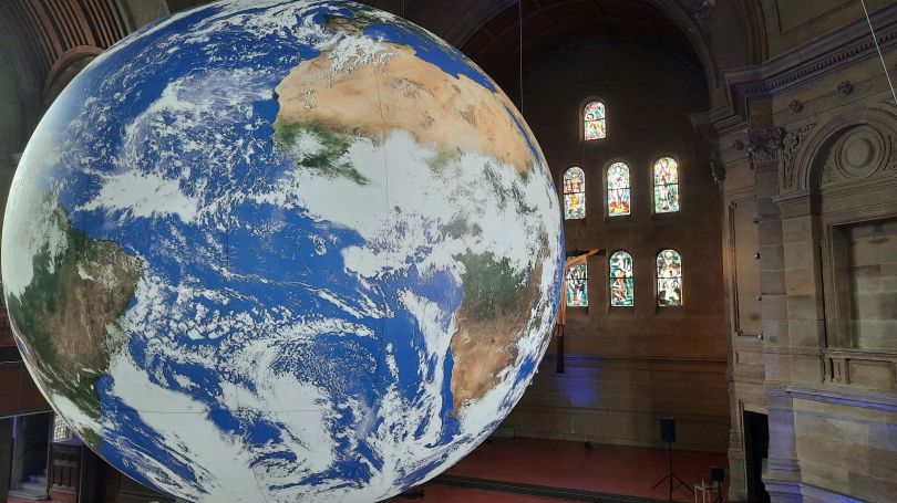 Erdkugel schwebt in Kirche als Kunstinstallation